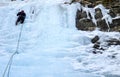 Male mountain guide lead ice climbing a frozen waterfall in deep winter in the Alps of Switzerland Royalty Free Stock Photo