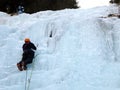 Male mountain guide lead ice climbing a frozen waterfall in deep winter in the Alps of Switzerland Royalty Free Stock Photo