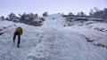 Male mountain guide rappelling off a steep frozen waterfall after an ice climbing excursion