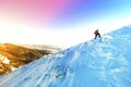 A male mountaineer walking uphill on a glacier. Mountaineer reaches the top of a snowy mountain in a sunny winter day. Royalty Free Stock Photo