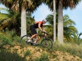 Male mountian biker on tropical trail, side view.