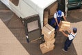 Male movers unloading boxes from van outdoors Royalty Free Stock Photo