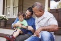 Male Multi Generation Family Sitting On Steps in Front Of House Royalty Free Stock Photo