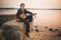 Male musician and his guitar on shore