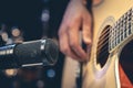 Male musician playing acoustic guitar behind microphone in recording studio. Royalty Free Stock Photo