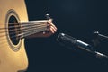 Male musician playing acoustic guitar behind microphone in recording studio. Royalty Free Stock Photo