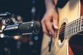 Male musician playing acoustic guitar behind microphone in recording studio. Royalty Free Stock Photo