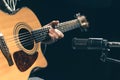 Male musician playing acoustic guitar behind microphone in recording studio. Royalty Free Stock Photo
