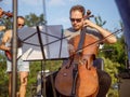 Male musician playing violoncello in orchestra outdoors