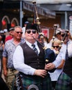 Male musician wearing a Scottish kilt is performing a lively tune in a parade in Dartmouth