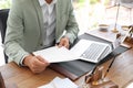 Male notary with documents and laptop at table in office