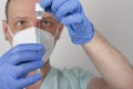 Male nurse with face mask and blue gloves, holding syringe with needle and covid-19 vaccine vial. Medical concept Royalty Free Stock Photo