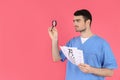 Male nurse holds magnifier and vision test on pink background