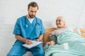 male nurse writing on clipboard while measuring blood pressure to smiling senior woman Royalty Free Stock Photo