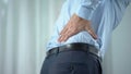 Male office worker feeling sharp back pain, standing up, sedentary lifestyle
