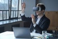 Male office worker in vr headset interacting with digital interface while sitting at desk Royalty Free Stock Photo