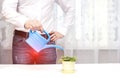 A male office worker is watering a flower from a watering can in the office, a red spot in the groin. The concept of prostate