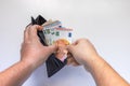 A male opening his wallet with Euro currency bills on a white table