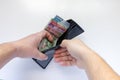 A male opening his wallet with Mexican currency bills on a white table