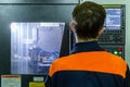Male operator stands in front of cnc turning machine while working. Close-up with selective focus.