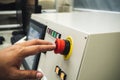 Male Operator use left hand to push emergency button to stop the machine