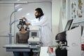 Male ophthalmologist with beard in white examining checking eye vision of patient with phoropter eyesight measurement Royalty Free Stock Photo