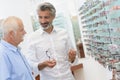 Male ophthalmologist helping customer in optics store