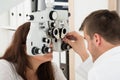 Male Optometrist Adjusting Phoropter While Examining Patient