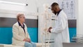 Male osteopath examining human skeleton bones to senior woman