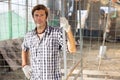 Male owner of livestock farm stands near corral mesh fence for livestock and rests