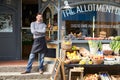 Male Owner Standing Next To Produce Display At Deli