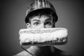 Male painter or decorator in hard hat with paint roller in front of face. Interior work with painting roller Royalty Free Stock Photo