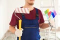 Male painter in uniform with roller brush and color palette samples indoors Royalty Free Stock Photo