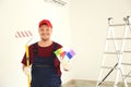 Male painter in uniform with roller brush and color palette samples indoors Royalty Free Stock Photo