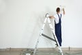 Male painter using roller for refurbishing color of wall indoors Royalty Free Stock Photo