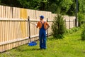 Male painter works at wooden fence