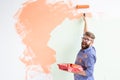 Male painting the wall with paint roller. Portrait of a funny guy painting wall in her new apartment. Redecoration and Royalty Free Stock Photo
