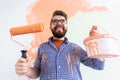 Male painting the wall with paint roller. Portrait of a funny guy painting wall in her new apartment. Redecoration and Royalty Free Stock Photo