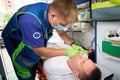 Male paramedic puts a drip on a patient in ambulance