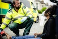 Male paramedic putting on an oxygen mask to an injured woman on a road