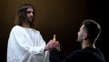 Male parishioner and Jesus praying holding burning candle together, faith symbol