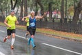 Male participant pointing to other people at long-awaited finish line while running on a city street during 21 km distance