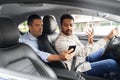 male passenger showing smartphone to car driver