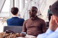 Male Passenger Sitting In Airport Departure Lounge Holding Passport Royalty Free Stock Photo