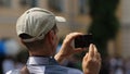 Male passer-by filming accident site on phone, defocused crowd of bystanders