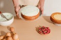 Male pastry chef is holding sponge cake with many various ingredients. Making sponge cake process