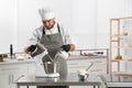 Male pastry chef preparing dough in mixer at table