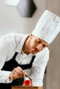 Male Pastry Cook Decorating Dessert In Kitchen