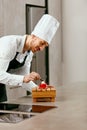 Male Pastry Cook Decorating Dessert In Kitchen