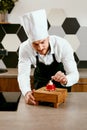 Male Pastry Cook Decorating Dessert In Kitchen